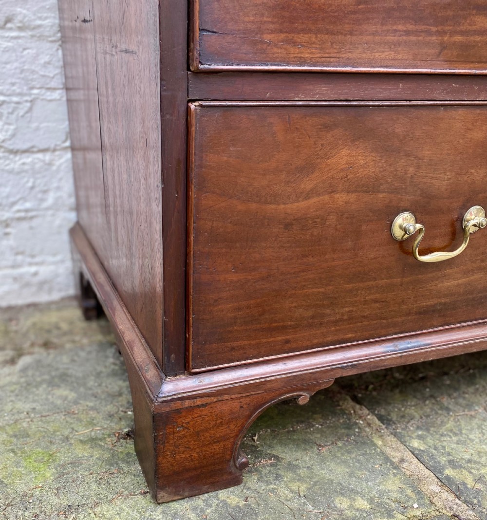A Georgian mahogany chest of drawers featuring two short drawers over three long drawers with brass swan-neck handles and shaped bracket feet. View III