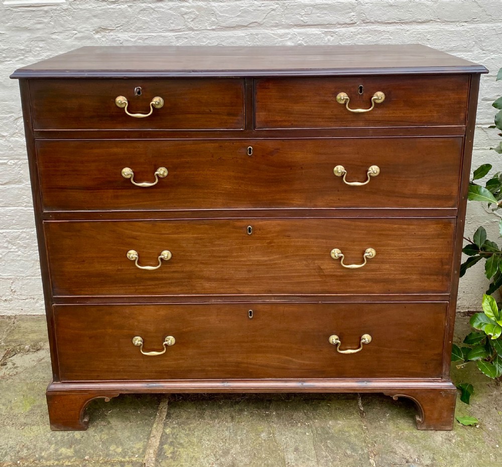 A Georgian mahogany chest of drawers featuring two short drawers over three long drawers with brass swan-neck handles and shaped bracket feet. View VIII