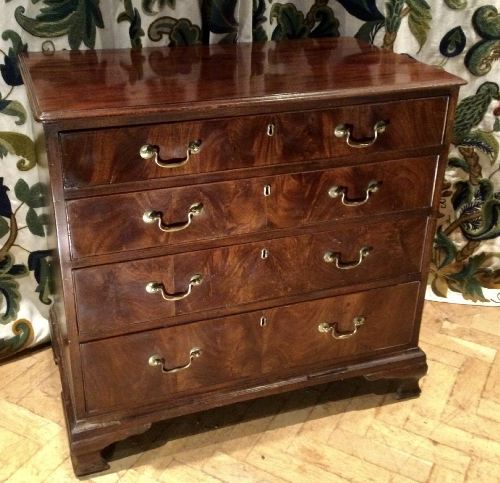 A small Georgian flame mahogany chest of drawers featuring four graduated long drawers with brass swan-neck handles and bracket feet.