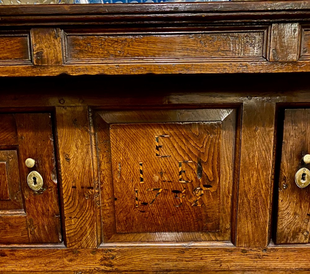 An antique dark oak Welsh tridarn cupboard featuring an open upper canopy shelf, fielded panel doors, small drawers, and turned drop finials. View III
