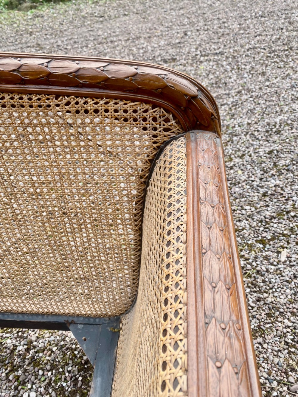 A French caned bergere sofa with a carved walnut frame, double-walled woven cane back, and a fabric seat cushion. View IV