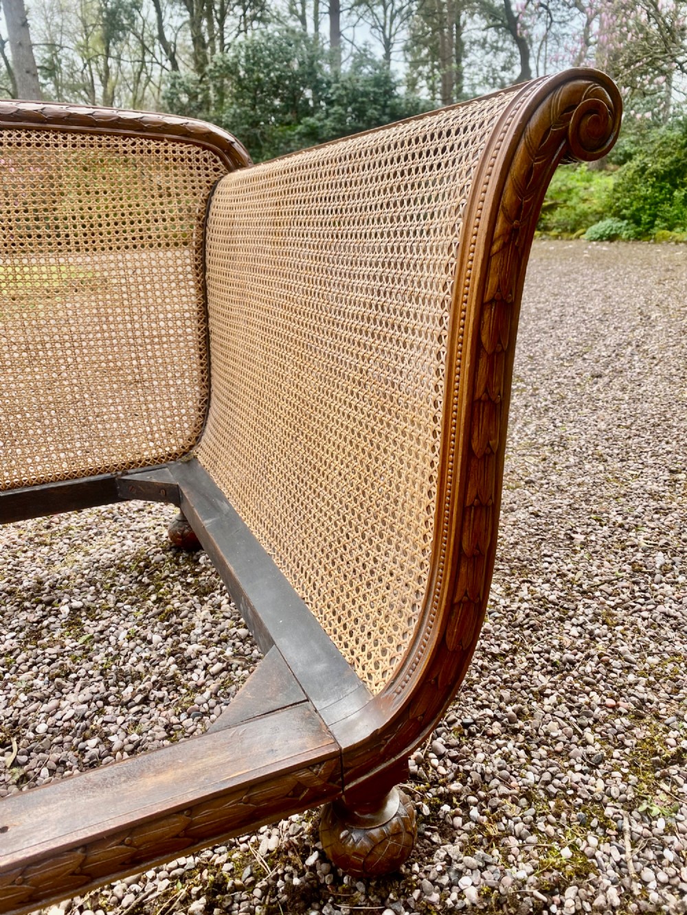 A French caned bergere sofa with a carved walnut frame, double-walled woven cane back, and a fabric seat cushion. View V