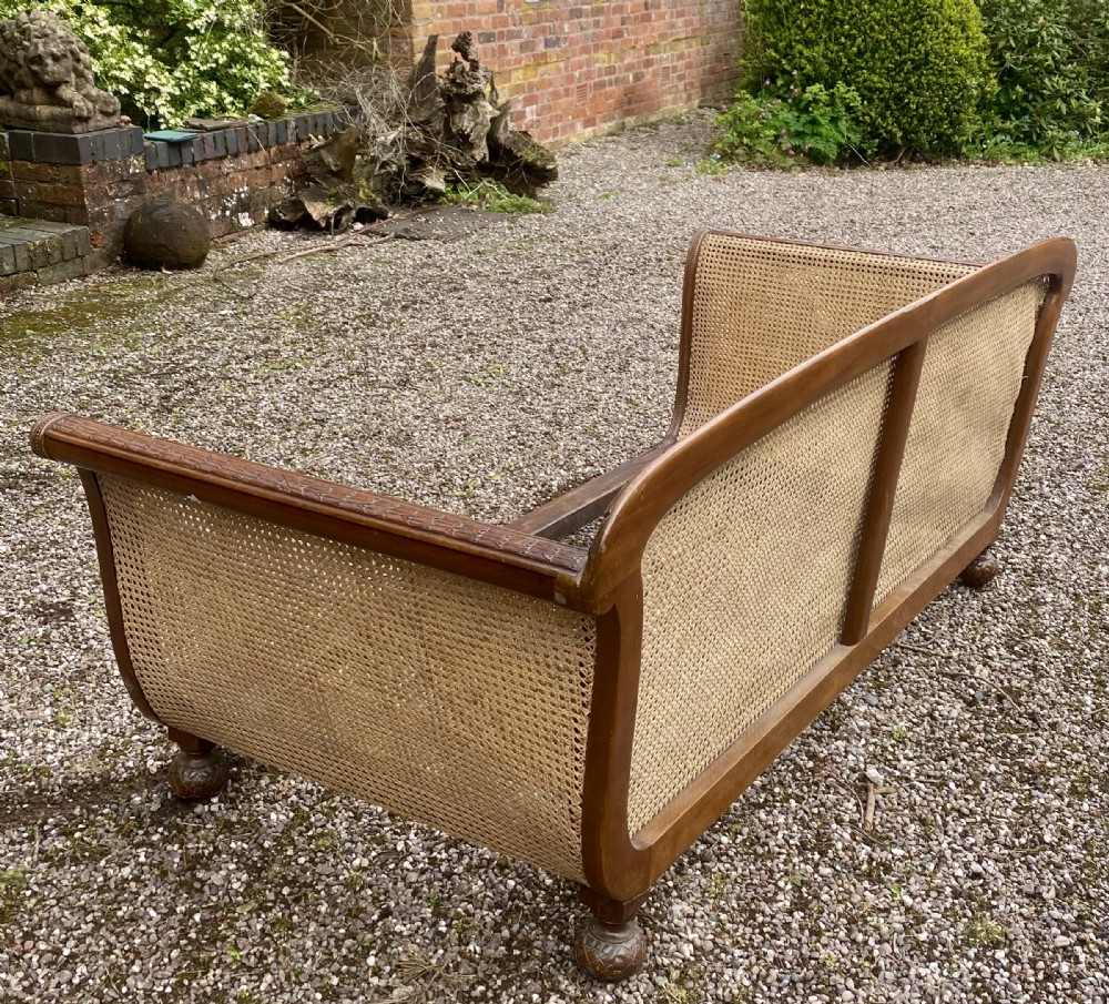 A French caned bergere sofa with a carved walnut frame, double-walled woven cane back, and a fabric seat cushion. View VI