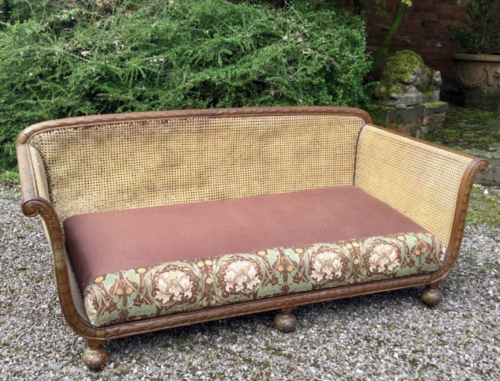 A French caned bergere sofa with a carved walnut frame, double-walled woven cane back, and a fabric seat cushion. View VIII