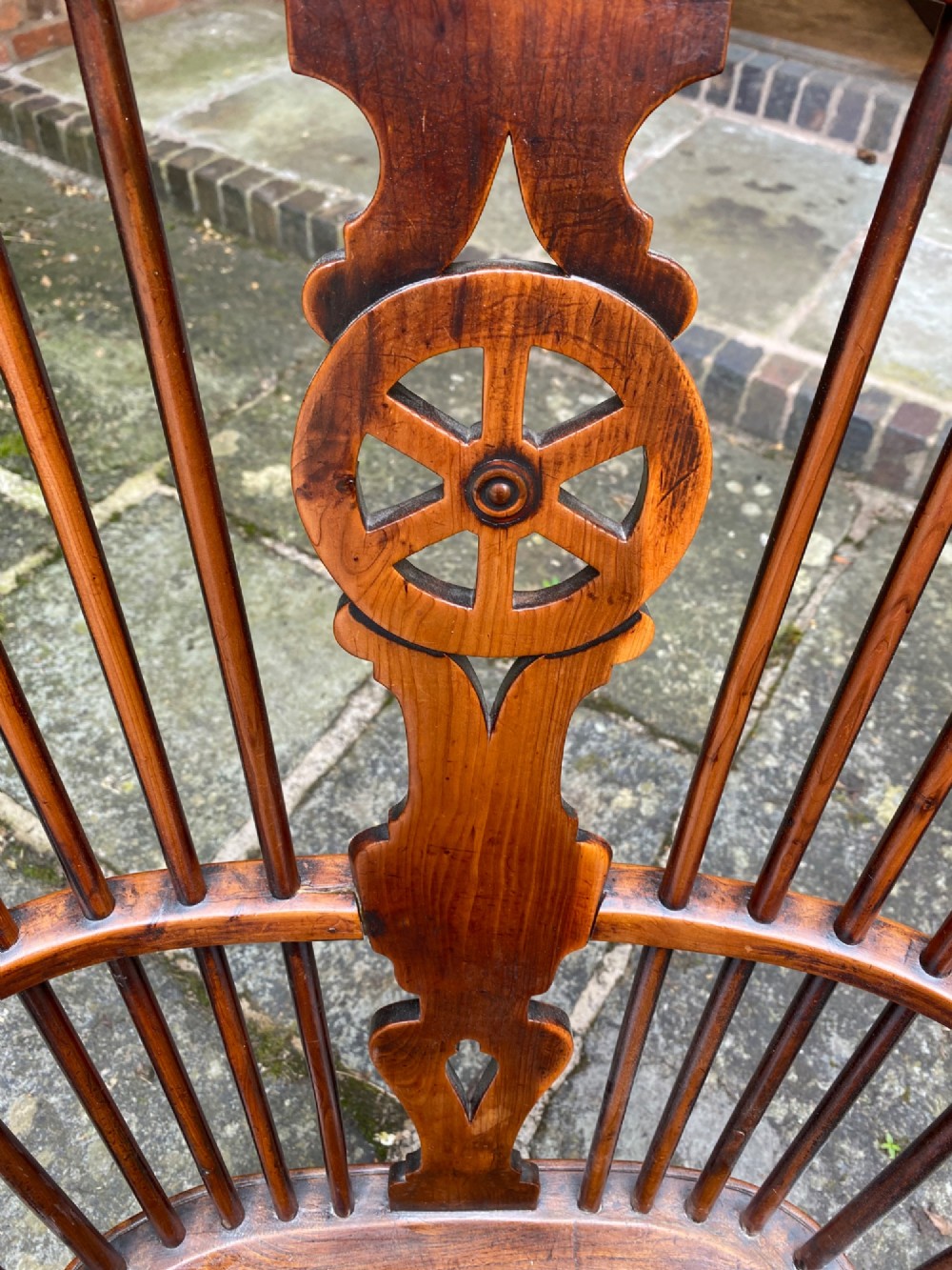 An antique yew wood Windsor armchair featuring a hoop back with a decorative wheelback splat, shaped saddle seat, and turned legs. View III
