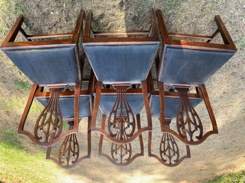 A set of mahogany dining chairs featuring carved openwork back splats, shaped armrests on the carver chairs, and dark fabric upholstered seat pads. View III