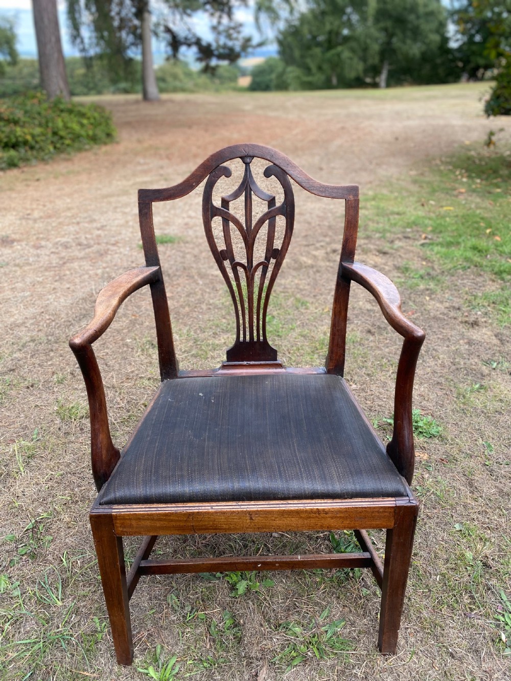 A set of mahogany dining chairs featuring carved openwork back splats, shaped armrests on the carver chairs, and dark fabric upholstered seat pads. View V