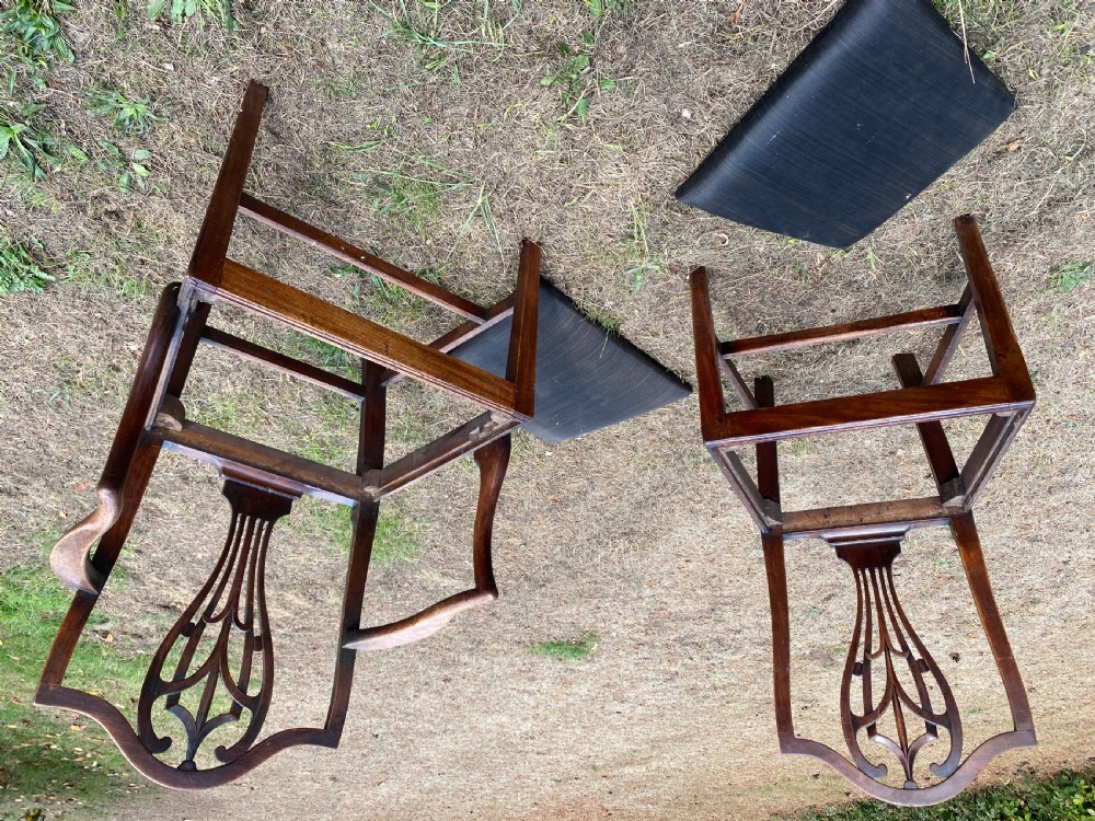 A set of mahogany dining chairs featuring carved openwork back splats, shaped armrests on the carver chairs, and dark fabric upholstered seat pads. View VI