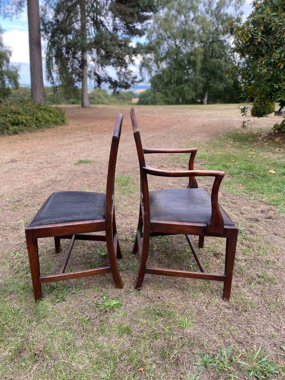 A set of mahogany dining chairs featuring carved openwork back splats, shaped armrests on the carver chairs, and dark fabric upholstered seat pads. View VII