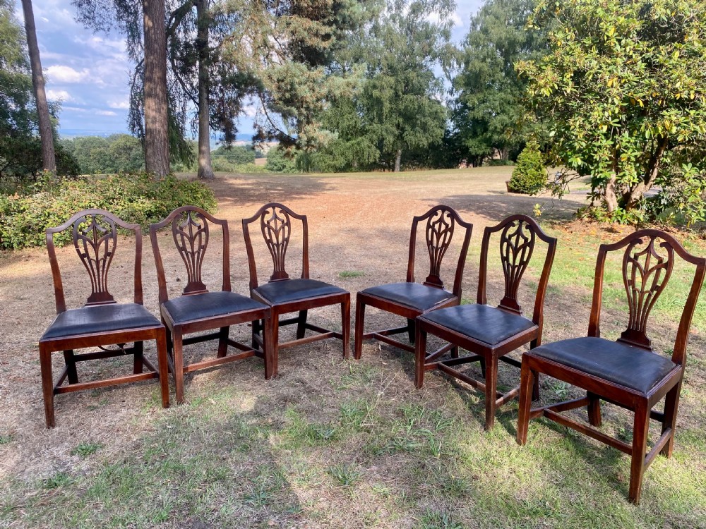 A set of mahogany dining chairs featuring carved openwork back splats, shaped armrests on the carver chairs, and dark fabric upholstered seat pads. View IX
