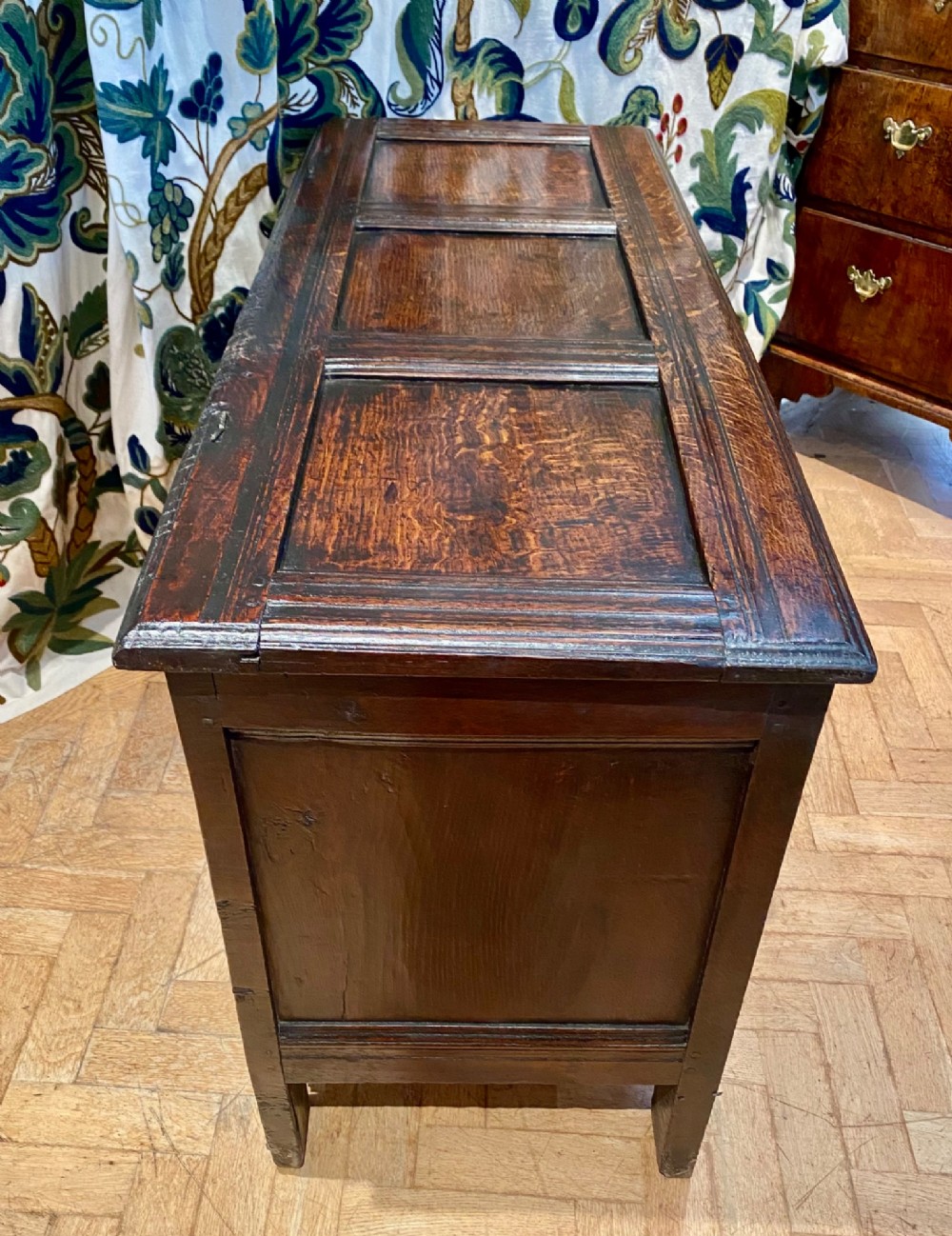 A dark carved oak coffer featuring a three-panel hinged top and three front panels decorated with carved diamond motifs and central rosettes. View IV