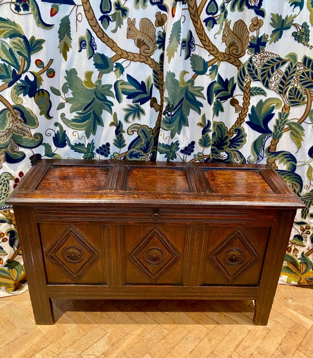 A dark carved oak coffer featuring a three-panel hinged top and three front panels decorated with carved diamond motifs and central rosettes. View VIII