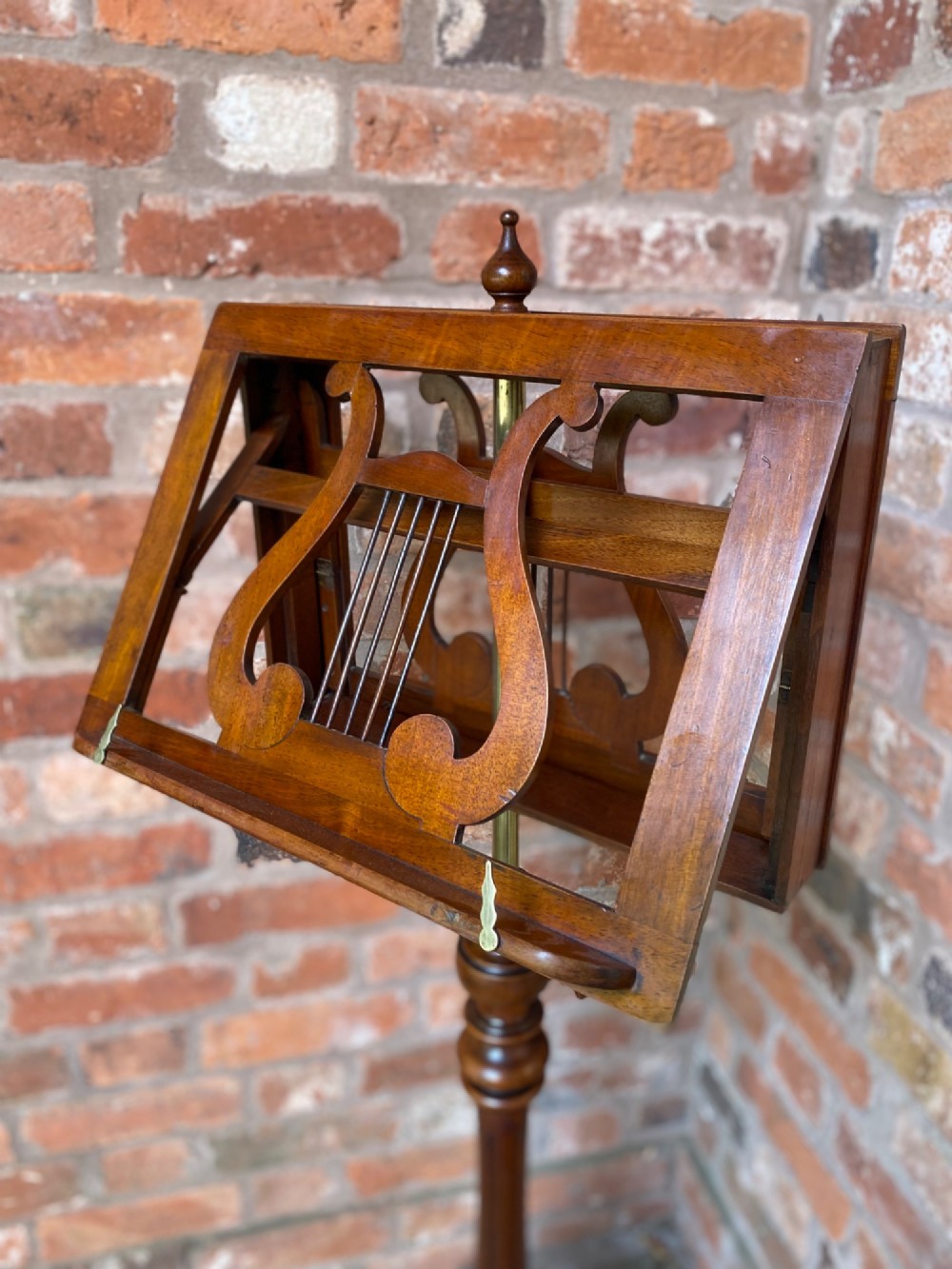 An antique mahogany duet music stand featuring double lyre-shaped rests, an adjustable brass stem, and a turned pedestal base on tripod feet. View III