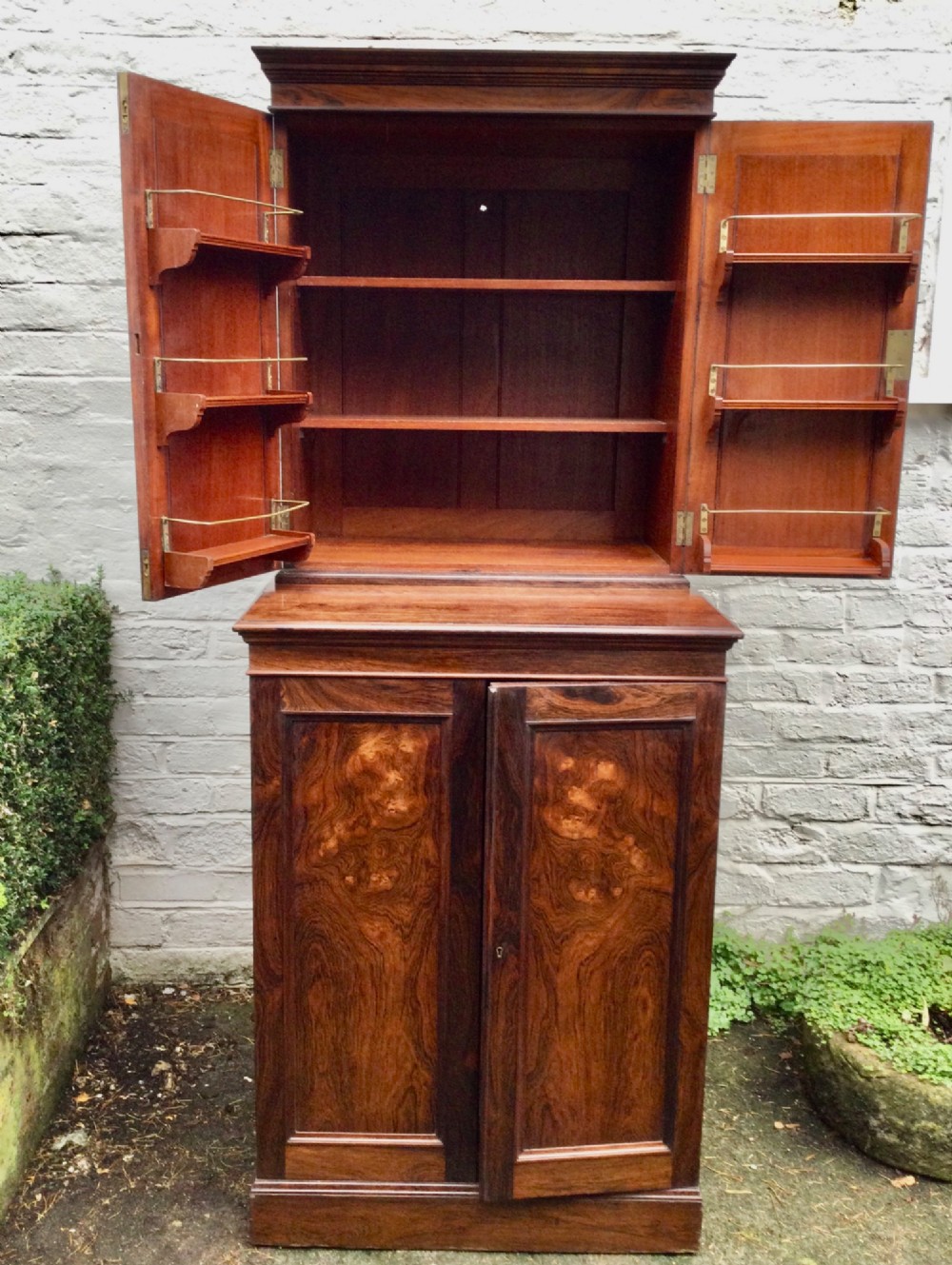 A tall two-tier dark rosewood cabinet with fielded panel doors, a moulded top cornice, and visible wood graining. View III