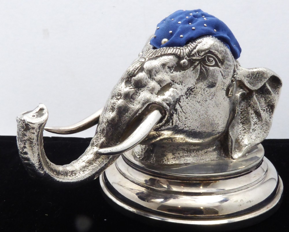 An antique silver pin cushion shaped as an elephant head on a stepped base with a blue velvet fabric insert on top. View III