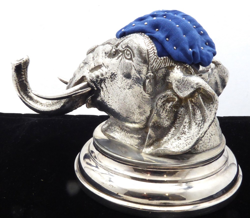 An antique silver pin cushion shaped as an elephant head on a stepped base with a blue velvet fabric insert on top. View IV