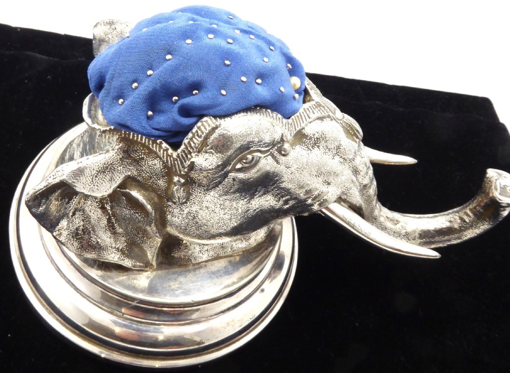 An antique silver pin cushion shaped as an elephant head on a stepped base with a blue velvet fabric insert on top. View VIII