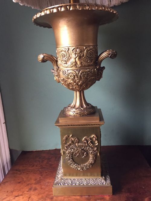 fig 1. Late 19th-century gilded bronze Empire style table lamp featuring a classical urn base with relief work and a fringed shade.