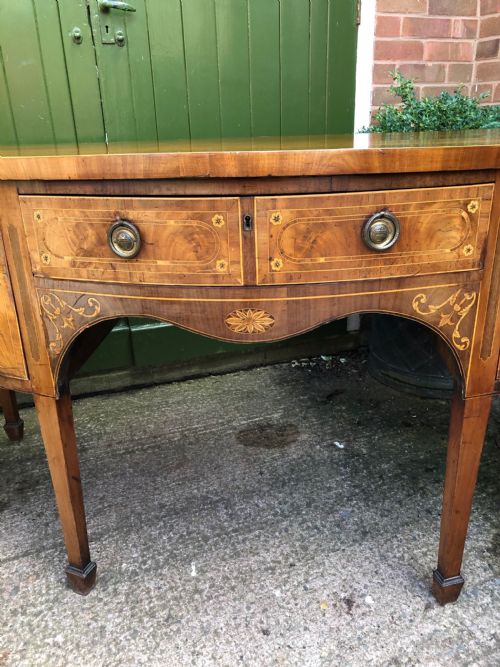 fig 3. A late 18th-century George III mahogany sideboard featuring a serpentine front, floral marquetry inlay, tapering square legs with spade feet, and brass oval handles.