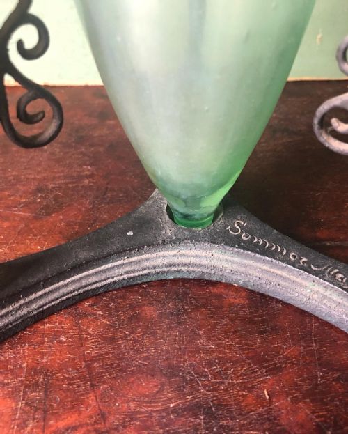 fig 1. A late 19th-century patinated bronze tripod stand with feline-headed legs holding a pale green glass amphora vessel.