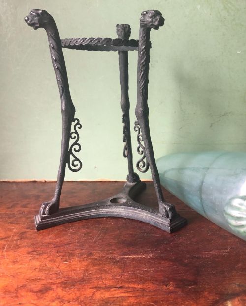 fig 2. A late 19th-century patinated bronze tripod stand with feline-headed legs holding a pale green glass amphora vessel.