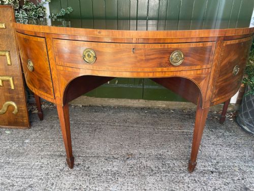 fig 2. A late 18th-century George III mahogany demi-lune sideboard featuring inlaid stringing, a central drawer, curved side doors, and tapered square legs.