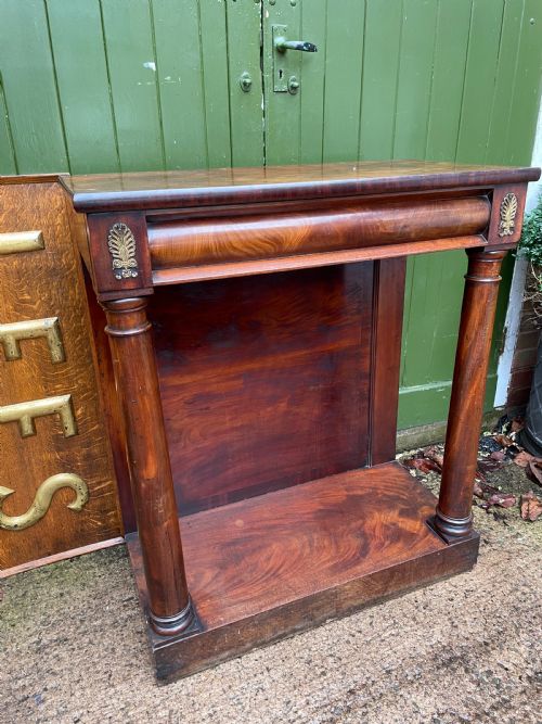 fig 1. Early 19th-century George IV mahogany console table featuring cylindrical front columns, brass mounts, a plinth base, and a flame mahogany backdrop.