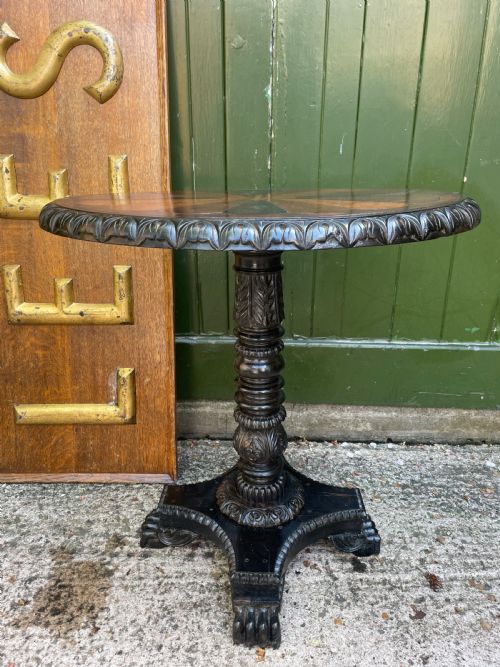 fig 1. A 19th-century Anglo-Indian pedestal table featuring a carved ebony base and a starburst inlaid specimen wood top.