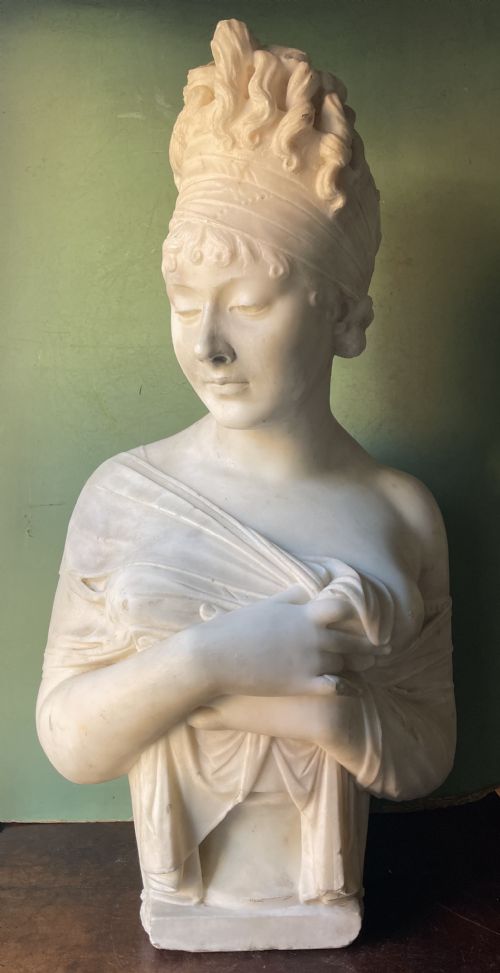 fig 1. A late nineteenth-century carved white statuary marble portrait bust depicting a female figure with draped cloth held across her chest and stylized hair.