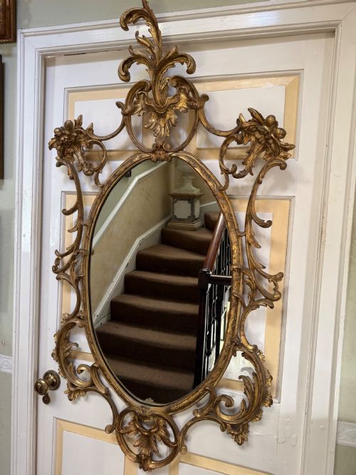 fig 1. Flamboyant early C20th carved gilt-wood and composition rococo-style framed oval mirror of C18th period design in the manner of Thomas Chippendale.