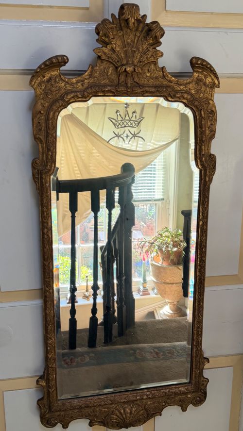 fig 1. A tall, slender carved giltwood pier mirror featuring an ornate acanthus leaf cresting and an etched crest motif near the top of the glass plate.