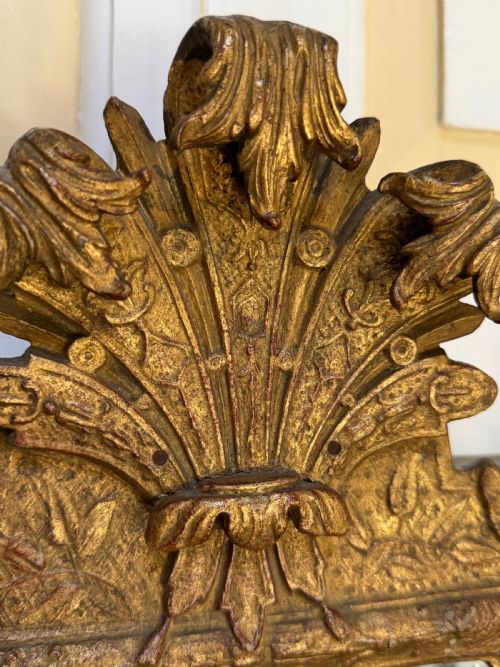 fig 2. A tall, slender carved giltwood pier mirror featuring an ornate acanthus leaf cresting and an etched crest motif near the top of the glass plate.