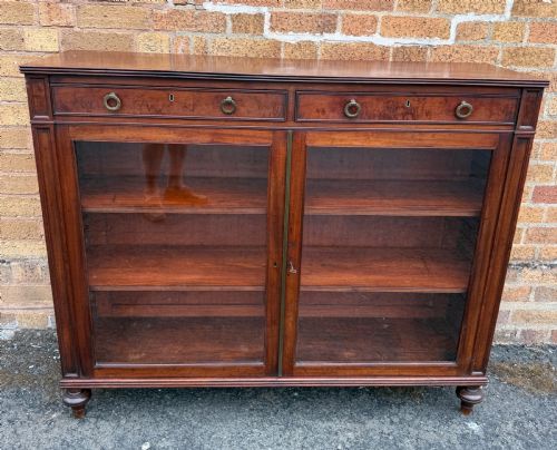 fig 1. An early nineteenth-century George III mahogany low bookcase featuring two top frieze drawers over glazed twin doors and turned feet.