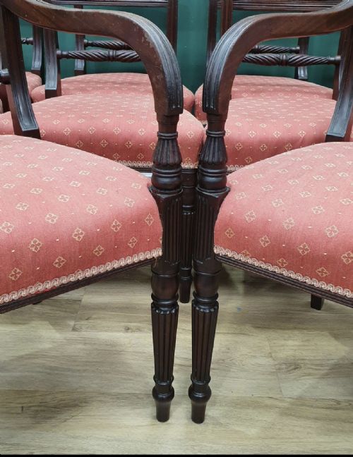 fig 1. A set of ten early nineteenth-century mahogany dining chairs featuring tablet top rails, reeded front legs, and patterned pink upholstered seats.