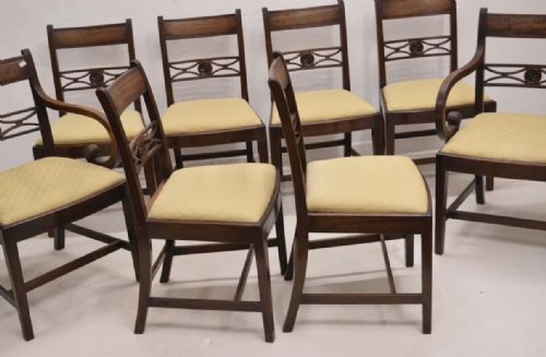 fig 1. A set of eight late eighteenth-century George III mahogany dining chairs, comprising six side chairs and two armchairs with carved back rails and patterned yellow upholstered seats.