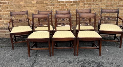 fig 2. A set of eight late eighteenth-century George III mahogany dining chairs, comprising six side chairs and two armchairs with carved back rails and patterned yellow upholstered seats.