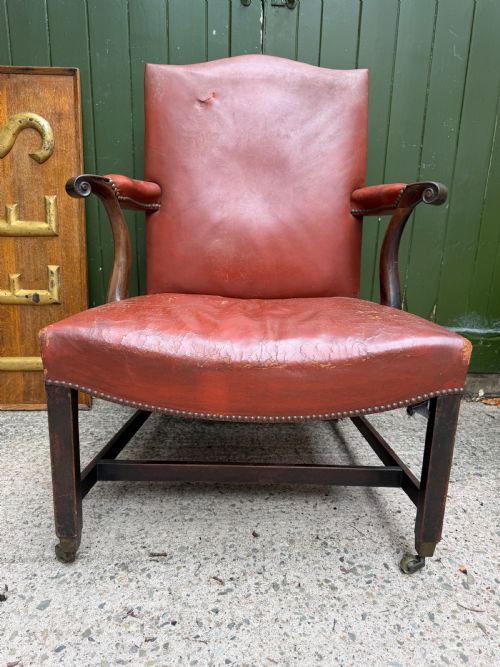 fig 1. An 18th-century George III Gainsborough library armchair upholstered in aged red leather with a mahogany frame, padded armrests, brass stud trim, and brass castors.