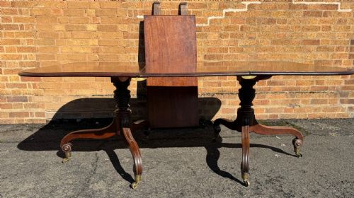 fig 1. An early 19th-century George III twin-pillar mahogany dining table featuring reeded splayed legs and original brass castors.