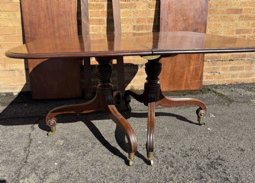 fig 2. An early 19th-century George III twin-pillar mahogany dining table featuring reeded splayed legs and original brass castors.