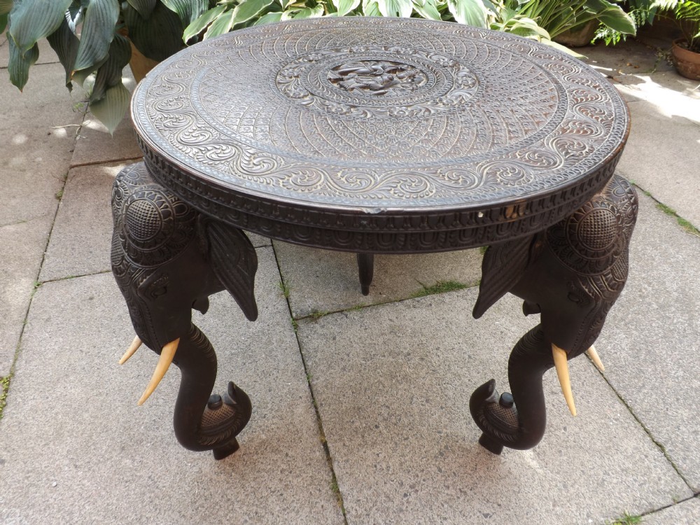 C19th Indian finely carved teak circular occasional table on elephant trunk supports.