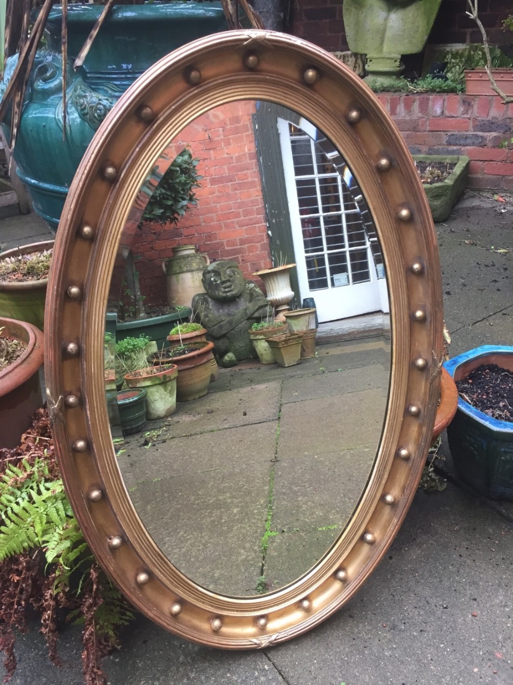 Late C19th oval giltwood-framed mirror in the Regency style.
