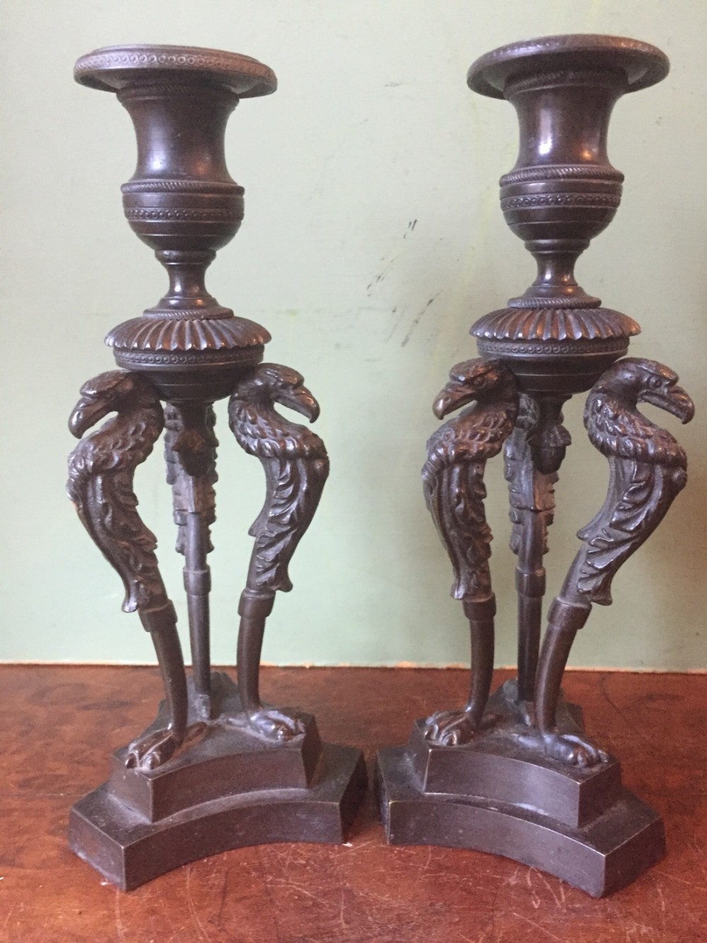 Pair of early C19th George IV period bronze candlesticks on triform stylised eagle or griffin supports.