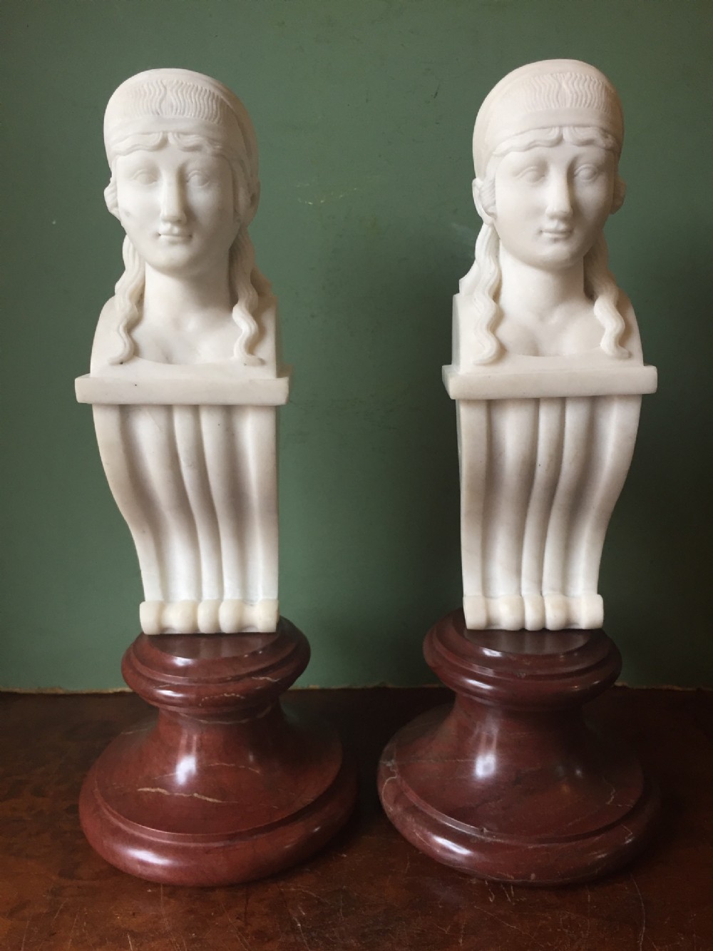 Pair of early C19th Regency period carved statuary marble female term figures in the manner of Thomas Hope, mounted upon rouge marble socles.