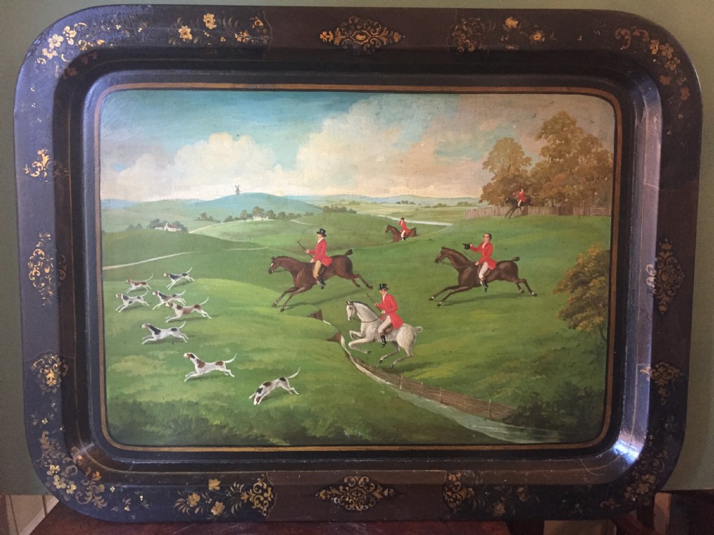 An early 19th-century rectangular papier-mache tray featuring a gilded scrollwork border and a central hand-painted scene of horsemen and hounds engaged in a fox hunt across a countryside landscape. View III