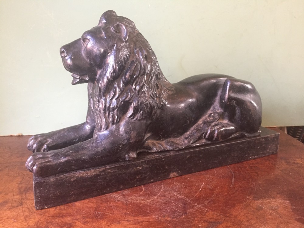 Late C19th cast-iron model of a recumbent lion on a rectangular plinth base.