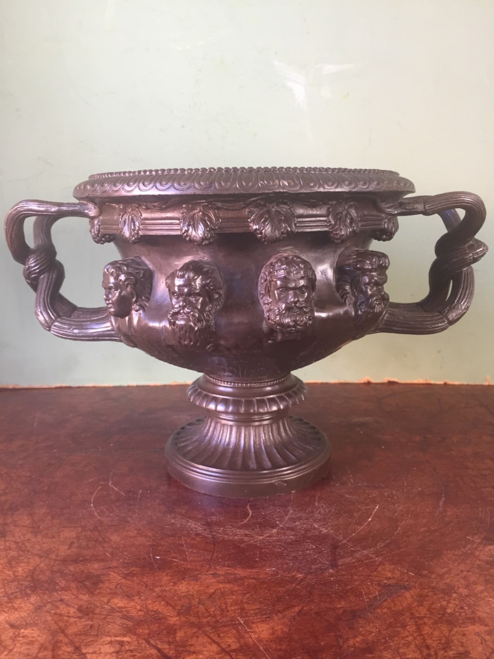 A nineteenth-century dark bronze reduction of the Albani Vase featuring classical sculpted masks along the body, intertwined handles, and a pedestal base.