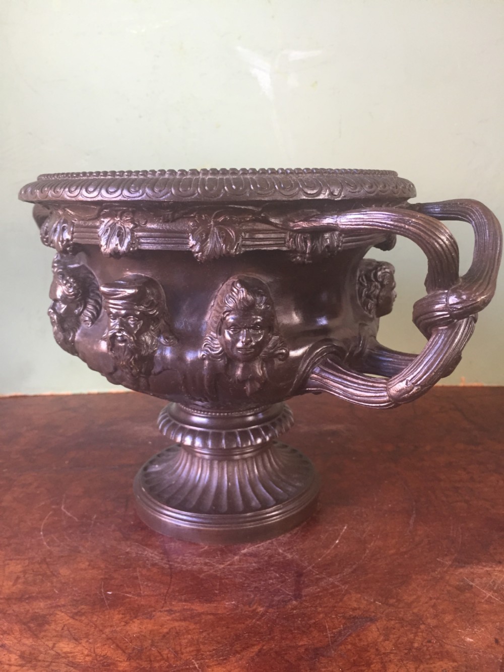 A nineteenth-century dark bronze reduction of the Albani Vase featuring classical sculpted masks along the body, intertwined handles, and a pedestal base. View VI