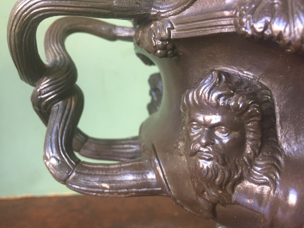 A nineteenth-century dark bronze reduction of the Albani Vase featuring classical sculpted masks along the body, intertwined handles, and a pedestal base. View X