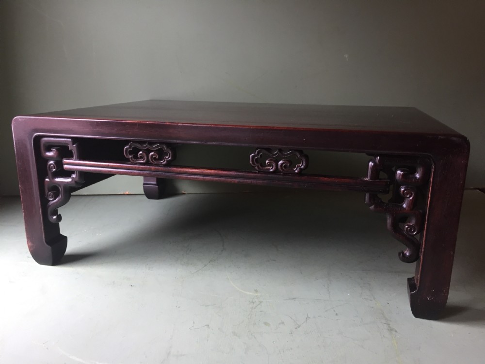 A late 19th-century Chinese dark hongmu hardwood scholars low table featuring carved cloud motif spandrels and straight legs.