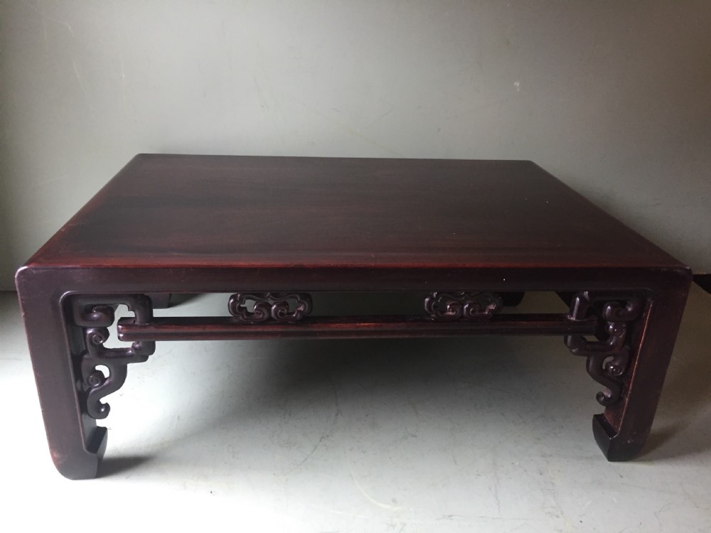 A late 19th-century Chinese dark hongmu hardwood scholars low table featuring carved cloud motif spandrels and straight legs. View V
